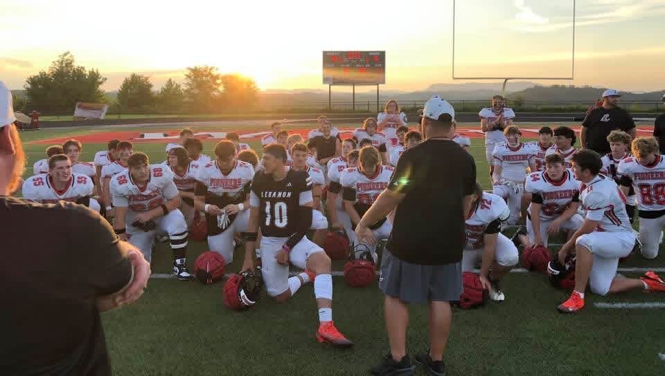 Football team huddled on the field at sunset