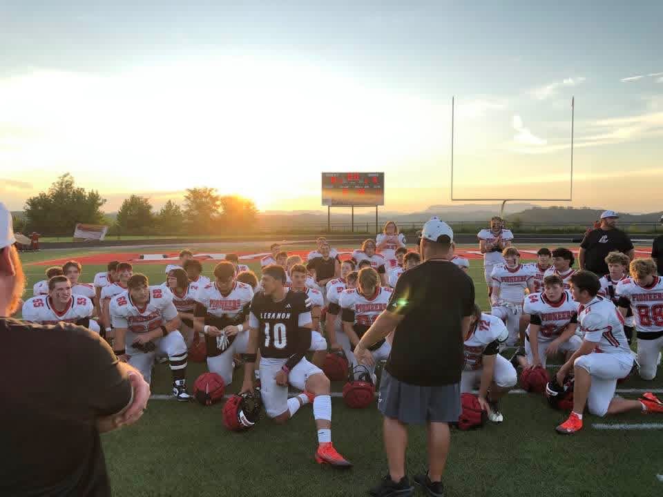 Football team huddled on the field at sunset